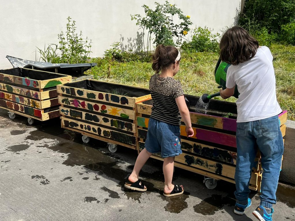 Kinder die ein Hochbeet gießen